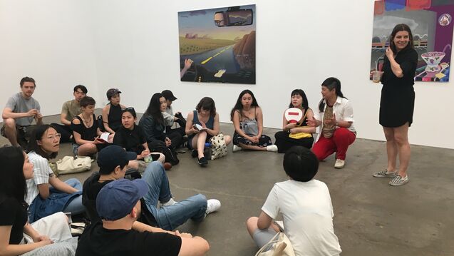 A group of students sitting and talking in a gallery.