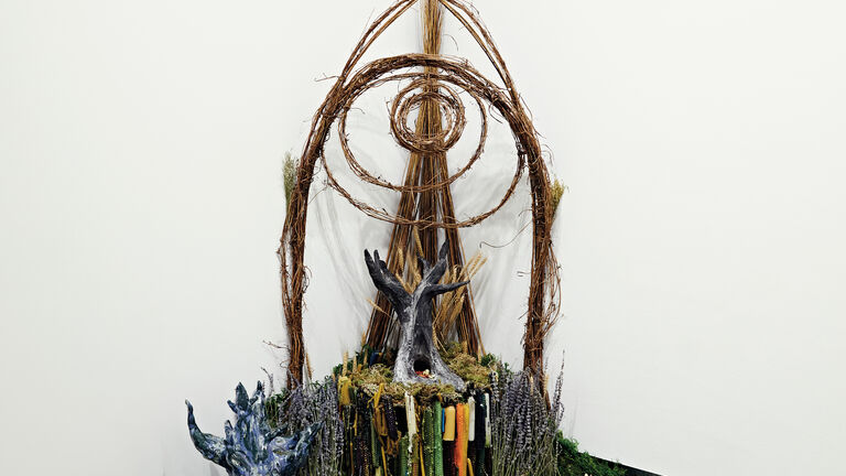 A large altar of sticks and wax in the corner of a gallery