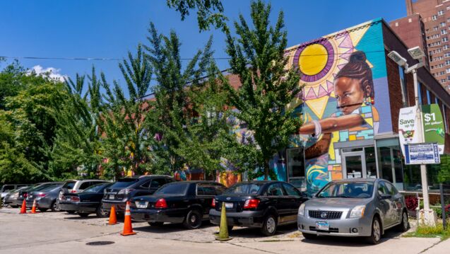 A mural in a parking lot with trees and cars.