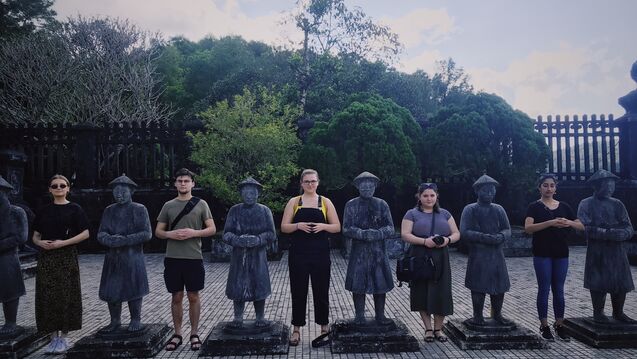 Students standing next to a series of statues.