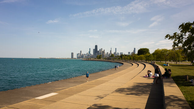 A concrete walkway in front of Lake Michigan. The Chicago skyline is in the background