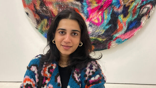 Tanya Malhotra stands in front of a colorful plus abstract artwork