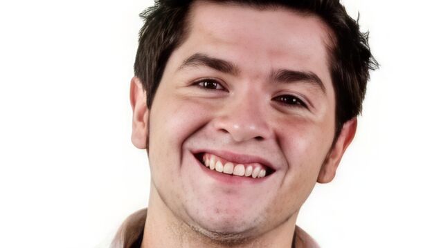 Headshot of an adult man smiling against a white background