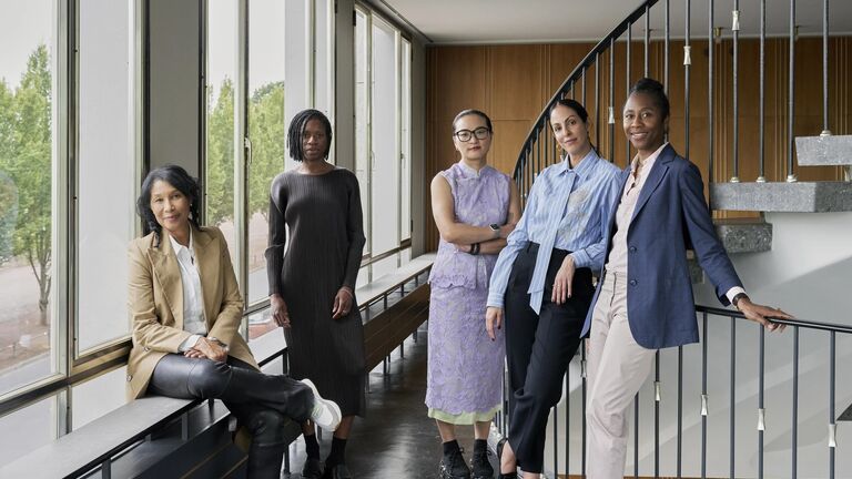 Five women stand and sit in a bright hallway by a staircase. From left: Naomi Beckwith, Carla Acevedo-Yates, Xiaoyu Weng, Mayra A. Rodríguez Castro, and Romi Crawford.