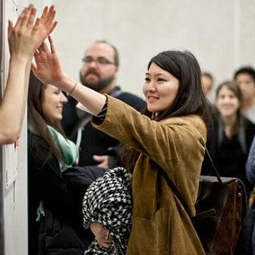 A group of international students giving high fives to SAIC team members.