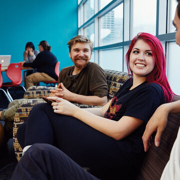 Students in a common area sitting on a couch and talking