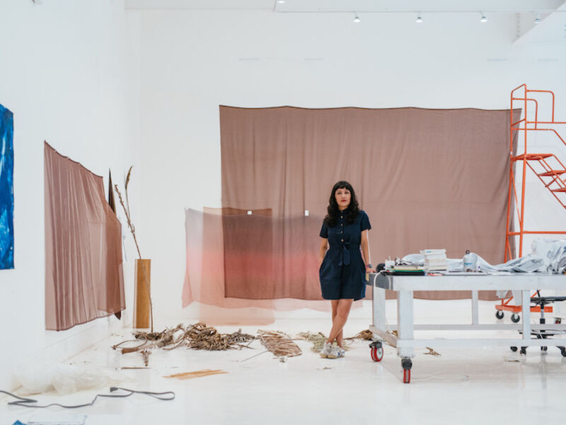 An artist leans against a table in a large, modern studio