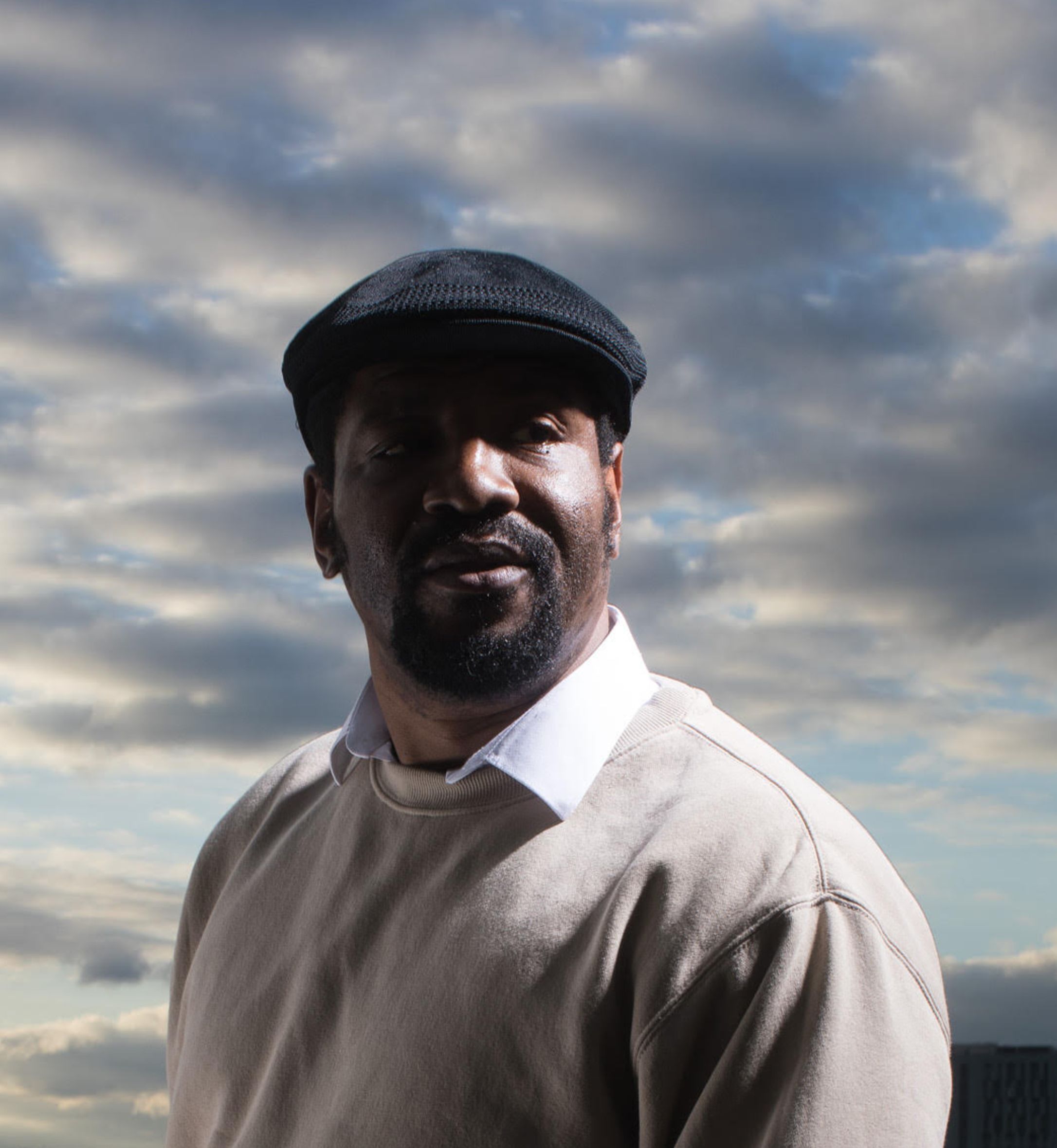 An artist poses in front of a sky background