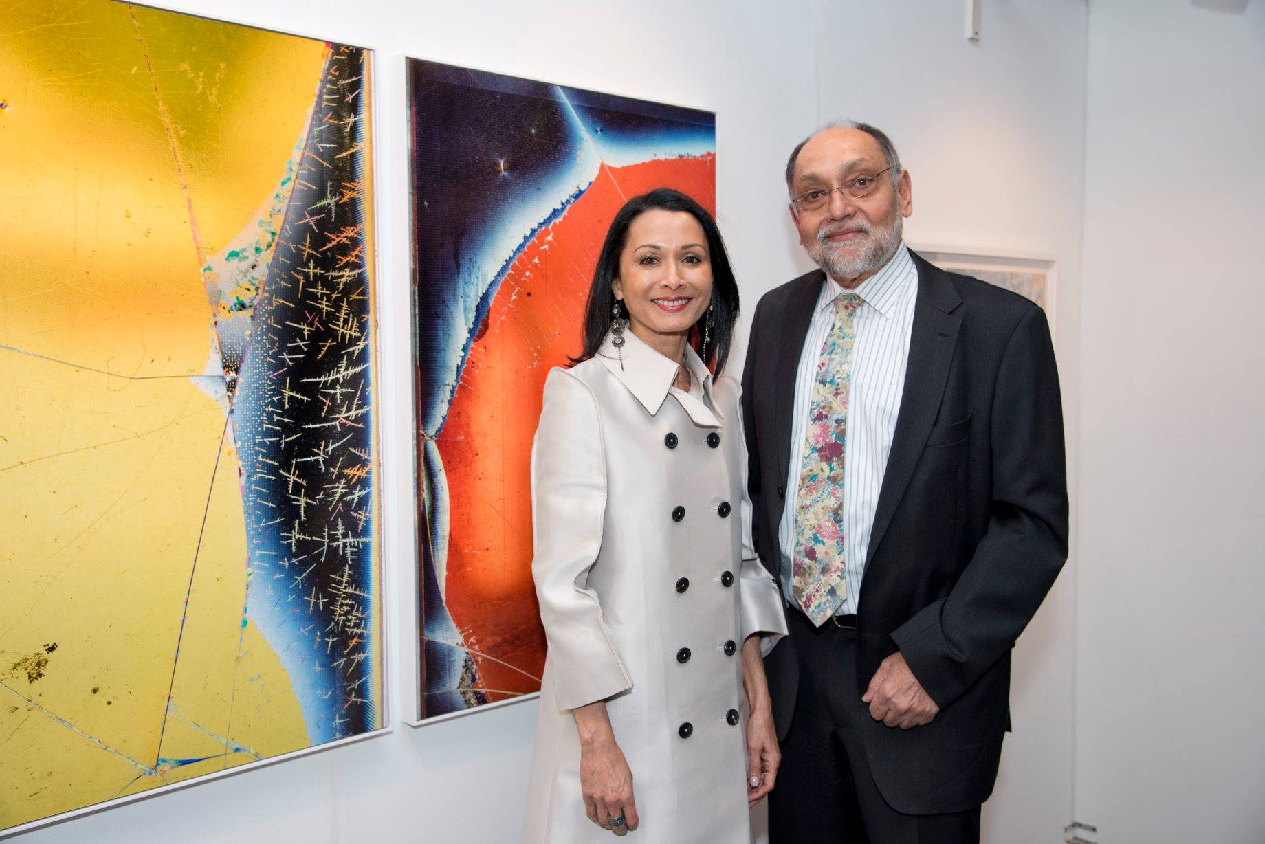 Anita and Prabha Sinha stand in front of an abstract canvas