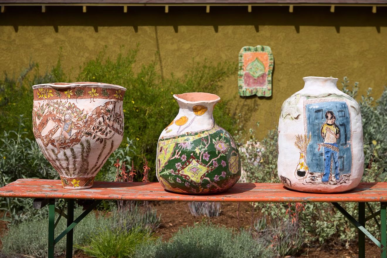 Rough, painted vases sit on a shelf