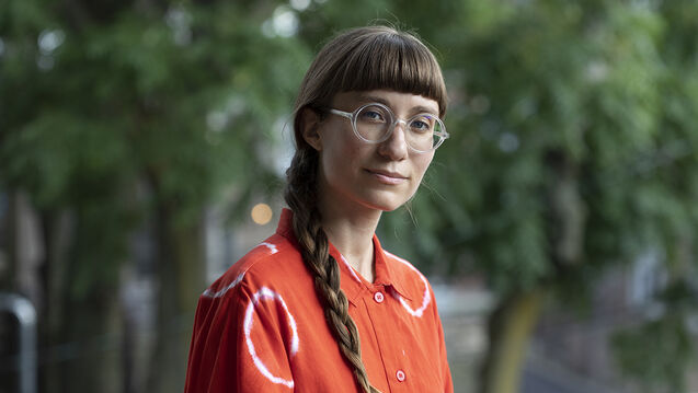 Kayla looks to the camera with a closed lipped smile, hair braided and resting on the right shoulder.