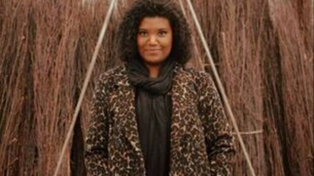 An arts administrator in a leopard coat poses in a field