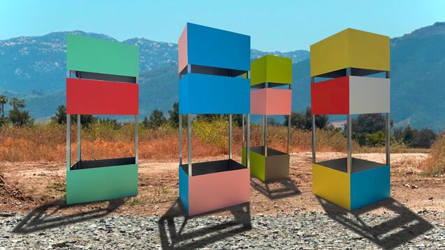 Multicolored cube structures in front of a mountainous desert landscape 