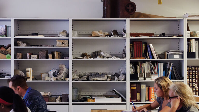 Students working in a classroom with various pieces on a series of shelves