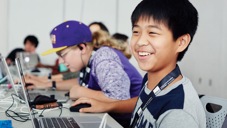 Students smile sitting at computers