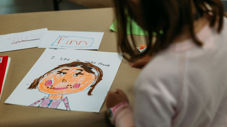 A student works on a drawing of a girl on a table