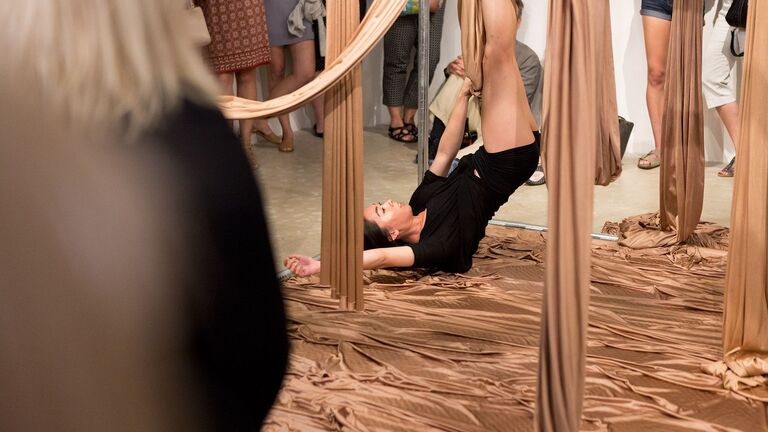 A person with their legs up in the air as part of an art performance. 