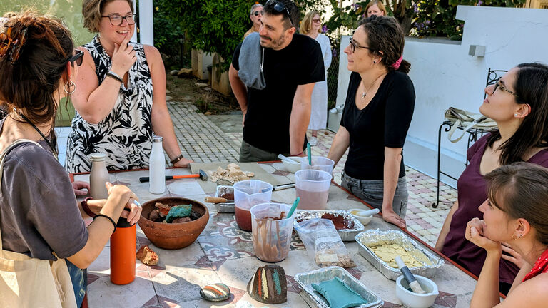 A gathering of friends and family around a table, celebrating with a variety of pigments in a warm atmosphere.