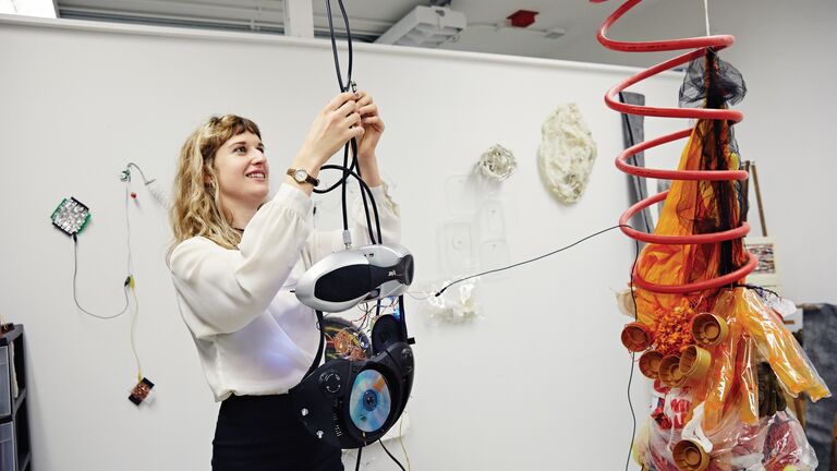 A photo of a woman interacting with an art installation in a gallery setting