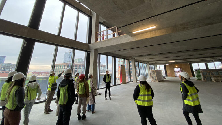 A group of people in neon vests and hard hats standing inside a building