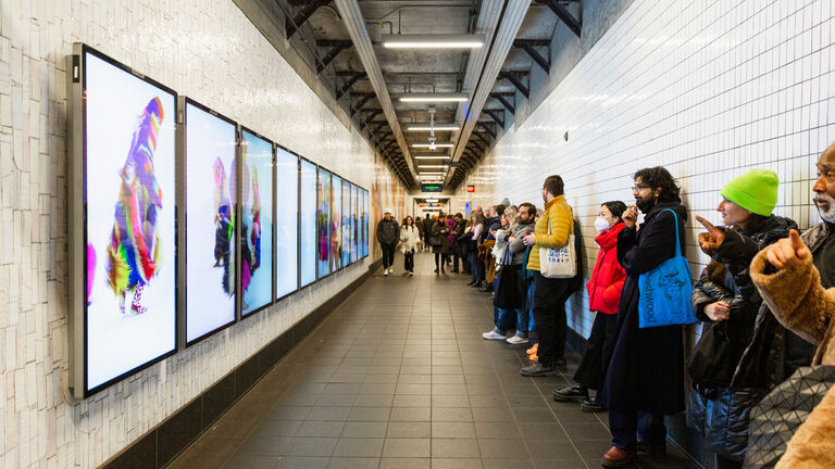 A group of people viewing screen art in a subway station