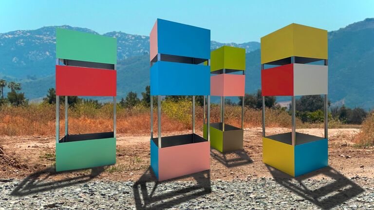 Multicolored cube structures in front of a mountainous desert landscape 