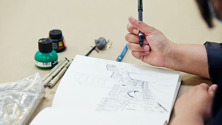 A detail of a student illustrating a cityscape.
