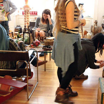 Students milling about the Roger Brown house, studying art objects and reading books.