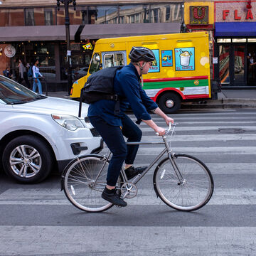 A biker bikes down a city street.