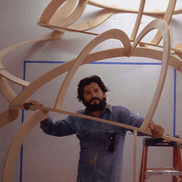 Juan standing underneath a wooden sculpture