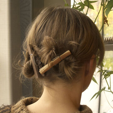 The back of a woman's head, hair held up with clothes pins.