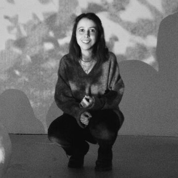Black and white image of Mariana squatting within an exhibit.