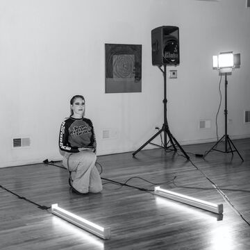 Bun kneels on one knee between two floor lights.