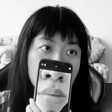 Ziyi holds a phone up to the lower half of her face, the screen facing out to enlarge her nose and lips for the viewer.