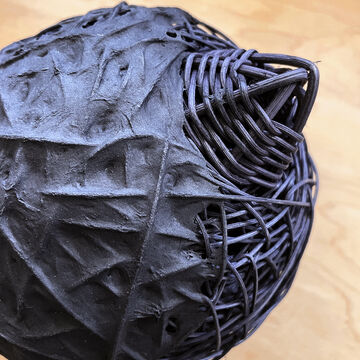 Detail shot of sculptural basket with paper dyed in black.