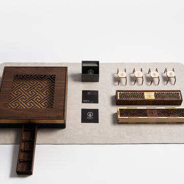 A designer utensil box that includes a set of cutlery, a custom leather mat, napkins, and bespoke packaging.