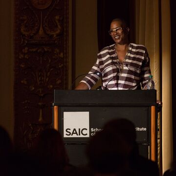 Black woman with glasses speaking at a podium