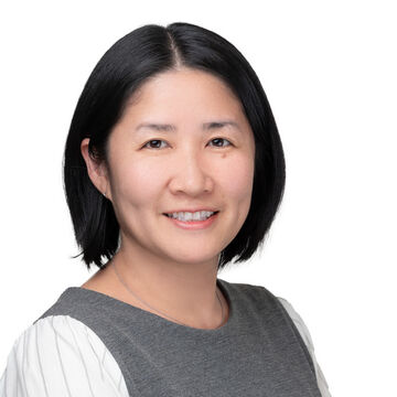 Headshot of an Asian woman smiling against a white background. 