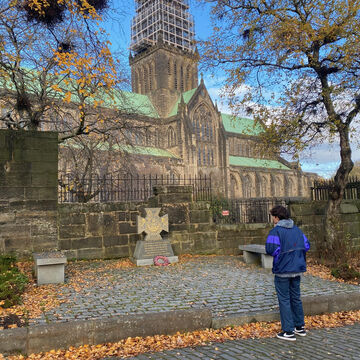 Man in a blue jacket standing in front of Glasgow Central Cathedral in the autumn