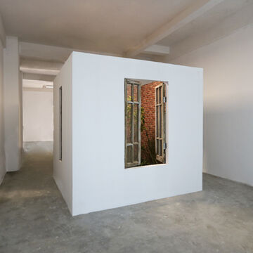 A white cubical structure in a gallery space, with a French-style window opening up to a space inside with brick walls, by Xingyu Huang