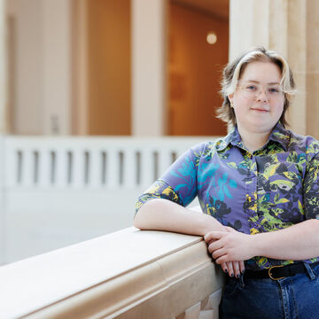 A student leans on a railing in a museum