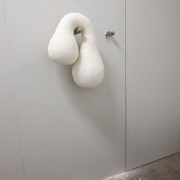 An organically shaped ceramic piece by Autumn Horwath, mounted on the wall via a peg. 