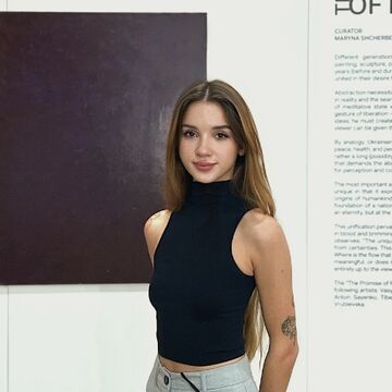 Photograph of Karyna Vovkotrub in front of a color field painting and wall text