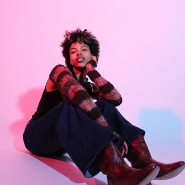 Photo of Isabel Padilla Bonelli sitting and posed on a soft pink backdrop