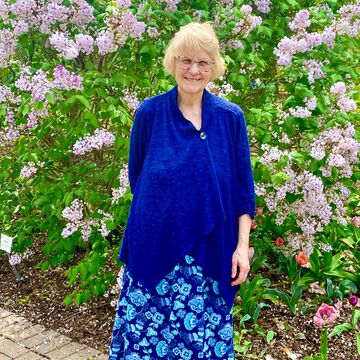 Portrait of an adult white woman standing in front of a flower bush