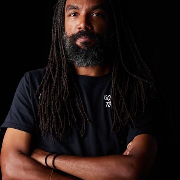 Headshot of a Black man with his arms crossed