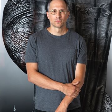 Portrait of a white man standing in front of an artwork