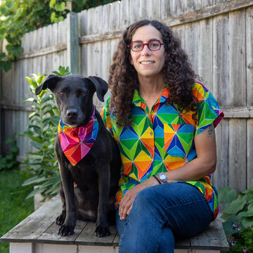 Portrait of an adult white woman seated outdoors next to a black dog