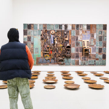 A person looking at a large piece of multi-media artwork in a gallery space