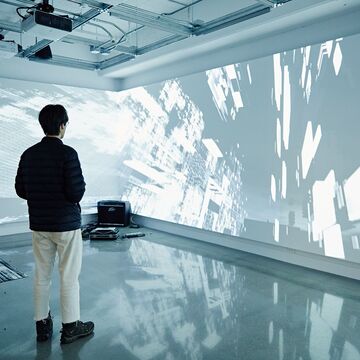 Cool-toned image of a person viewing an art installation in a gallery space. 